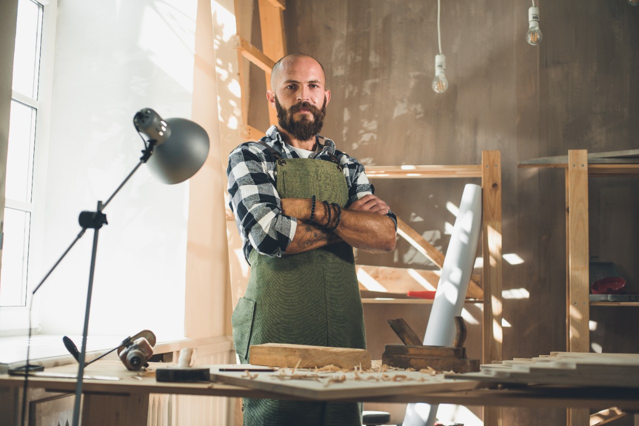 Portrait of a young male carpenter who works in his workshop using hand tools.