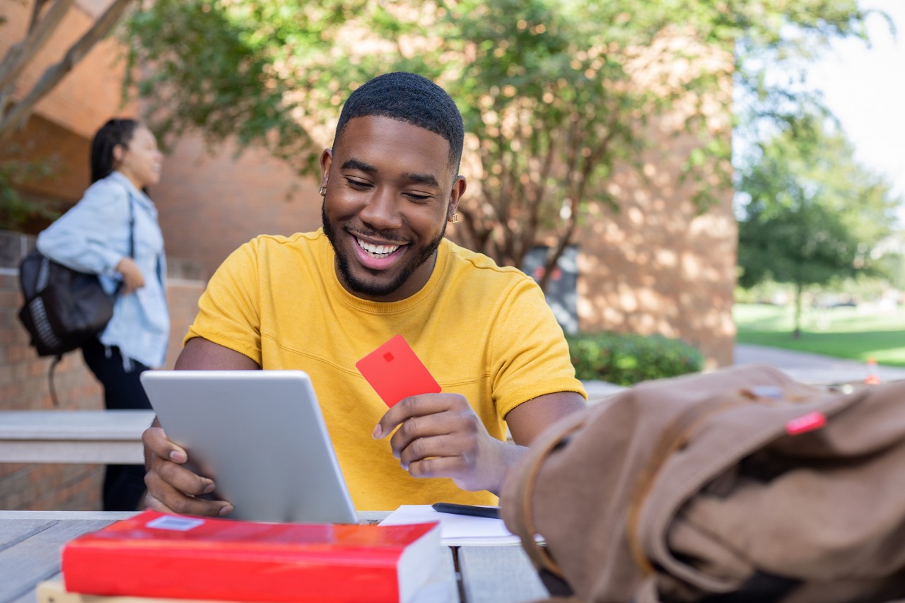 Adult male student smiles while studying outdoors