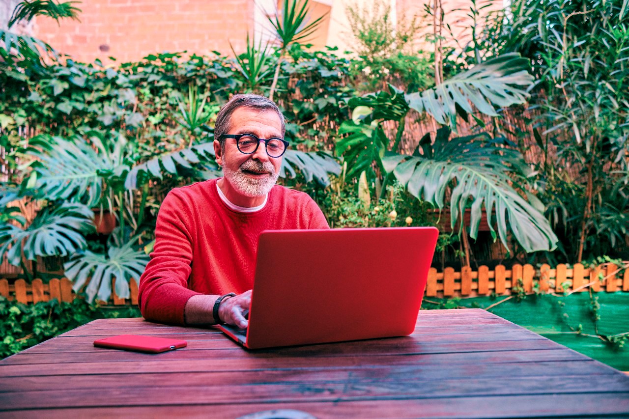 a senior man working in his garden with a laptop computer